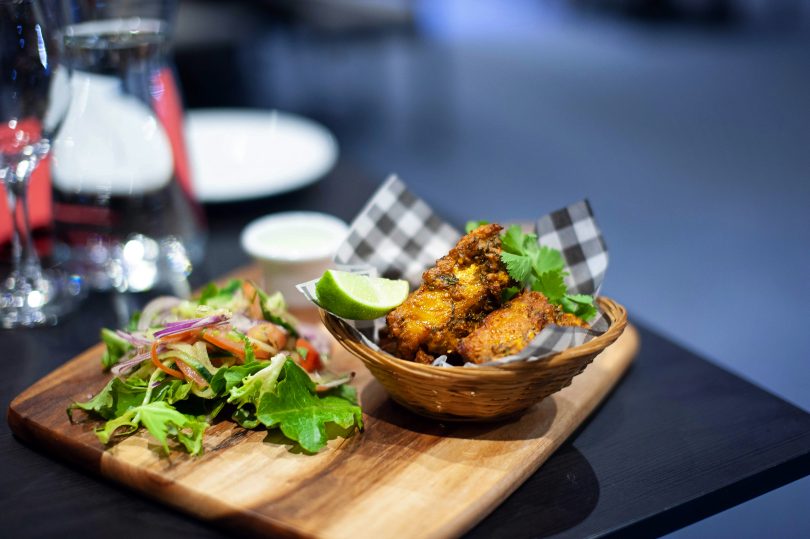 Dish of fried fish in a basket with salad on side.