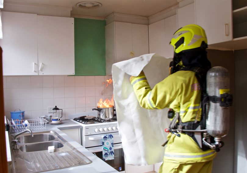 Firefighter about to put fire blanket on kitchen fire