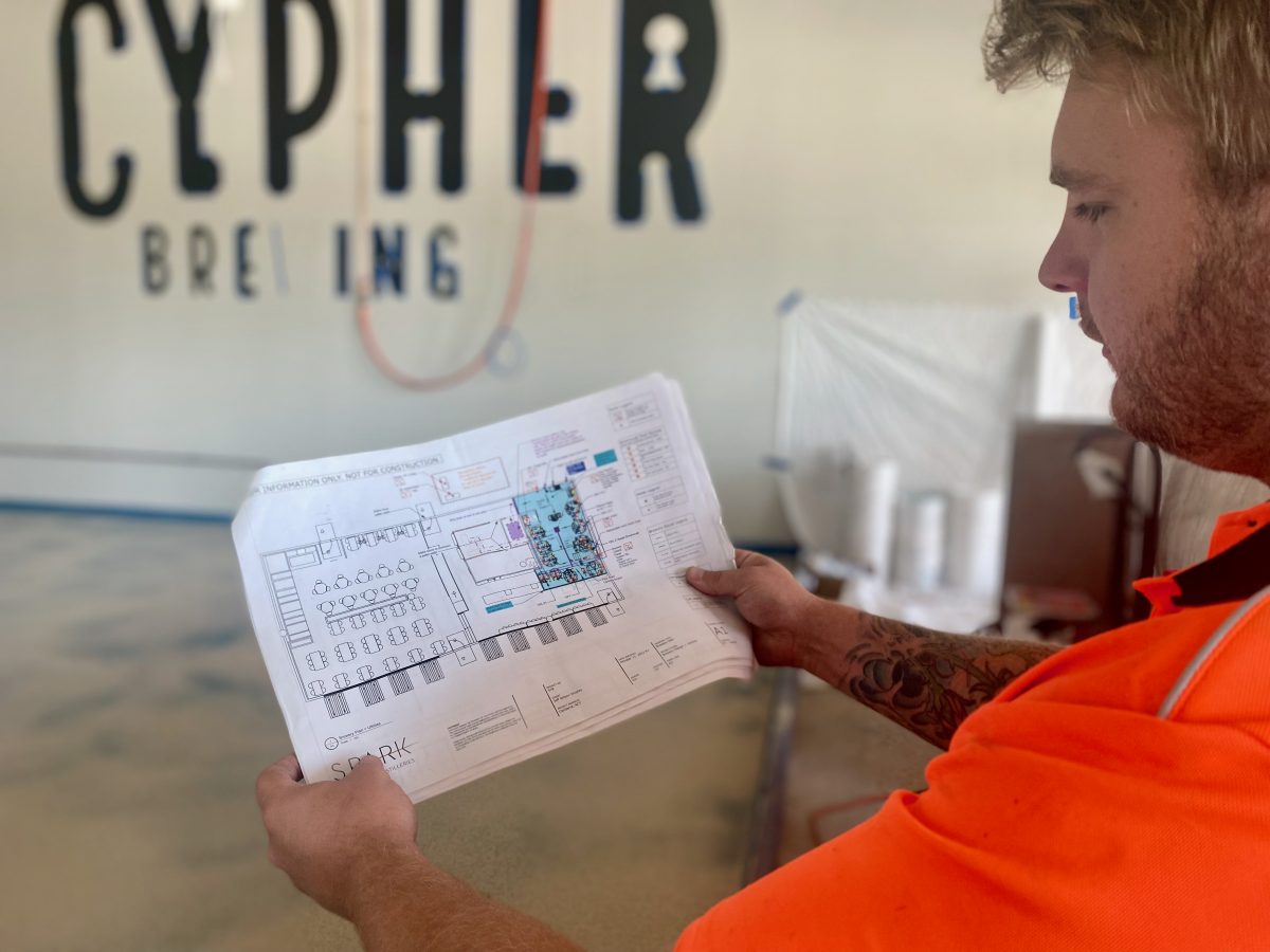 Jeff, wearing high vis, studies the Cypher Brewing Co architectural plans