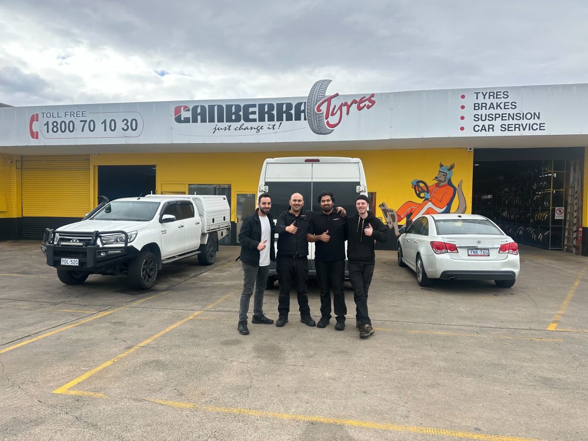 four men giving the thumbs up in front of Canberra Tyres