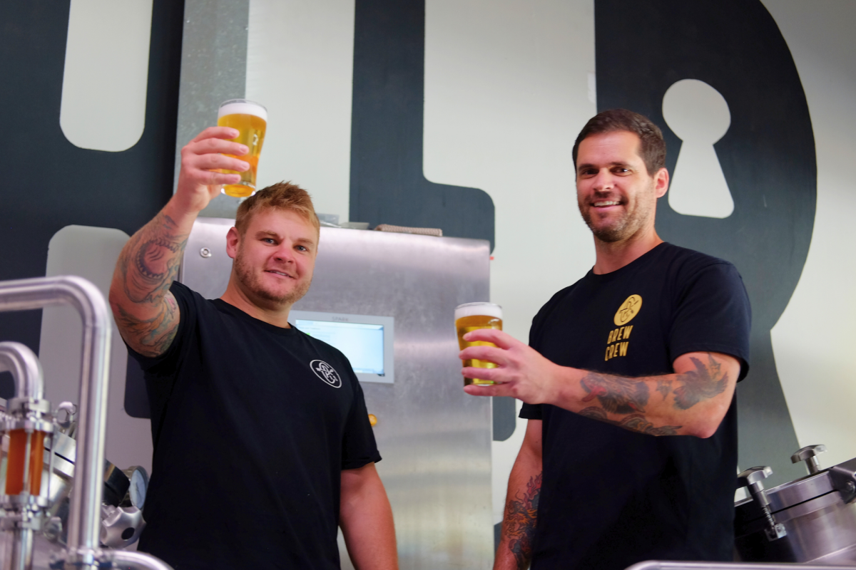 Two men raising beer glasses in cheers.