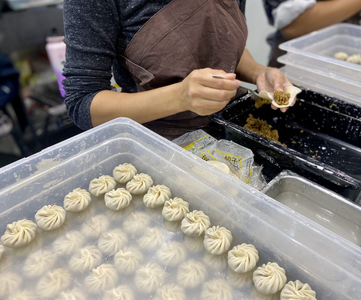 An action shot of hands making small, beautifully twisted dumplings.